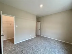 Neutral tone wall paint, recessed lighting, carpeted flooring, and a closet with built-in wire shelving