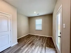 Wood-finish flooring, neutral wall tones, recessed lighting, a window with blinds, and a glass-paneled door