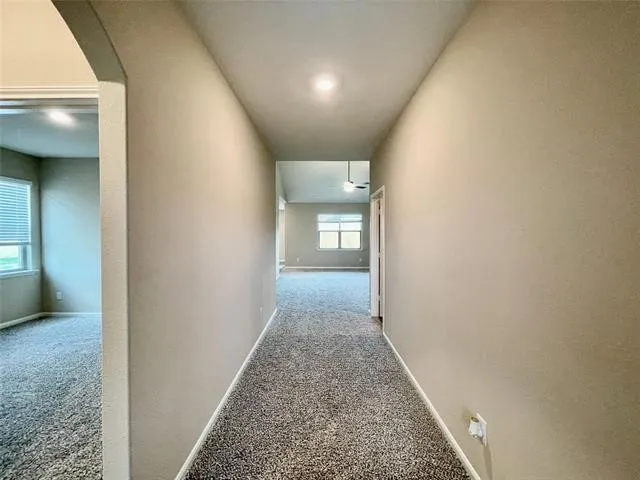 Carpeted hallway with recessed lighting and neutral wall tones