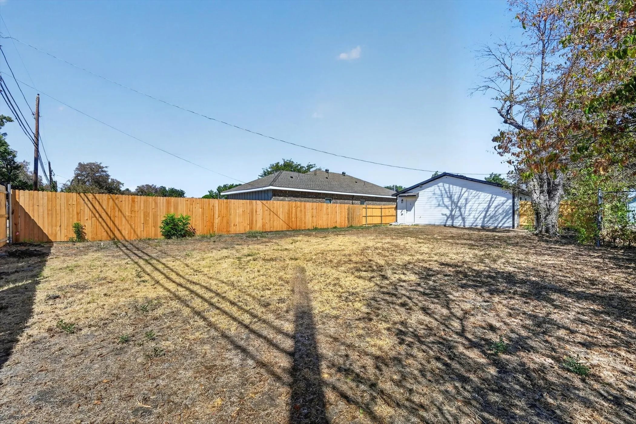 Expansive backyard featuring a wood privacy fence and mature trees