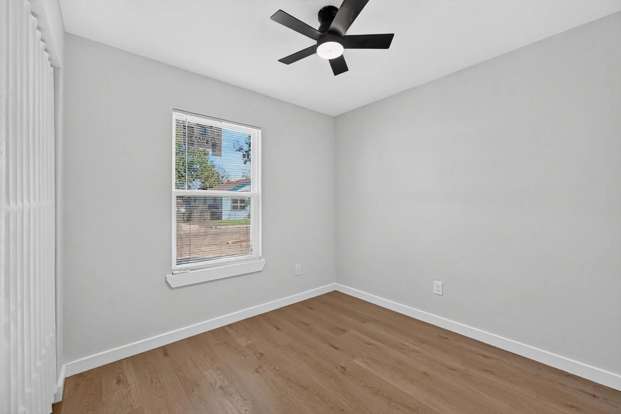 Wood-finish flooring, white walls, and a ceiling fan with integrated lighting
