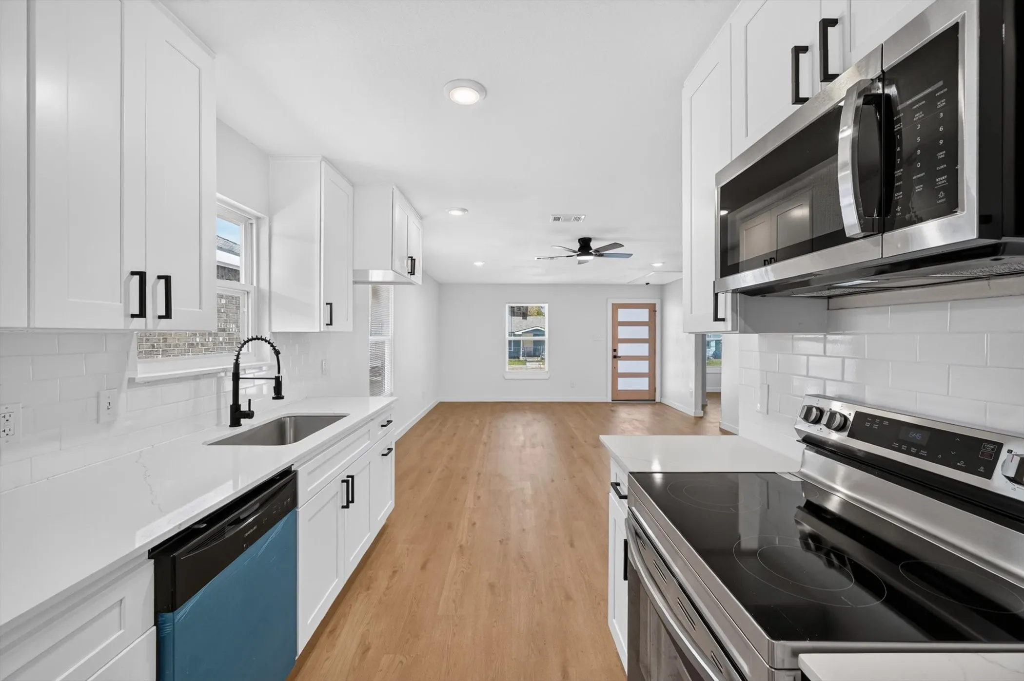 Modern kitchen featuring white shaker cabinetry, stainless steel appliances, a subway tile backsplash, and light-toned countertops