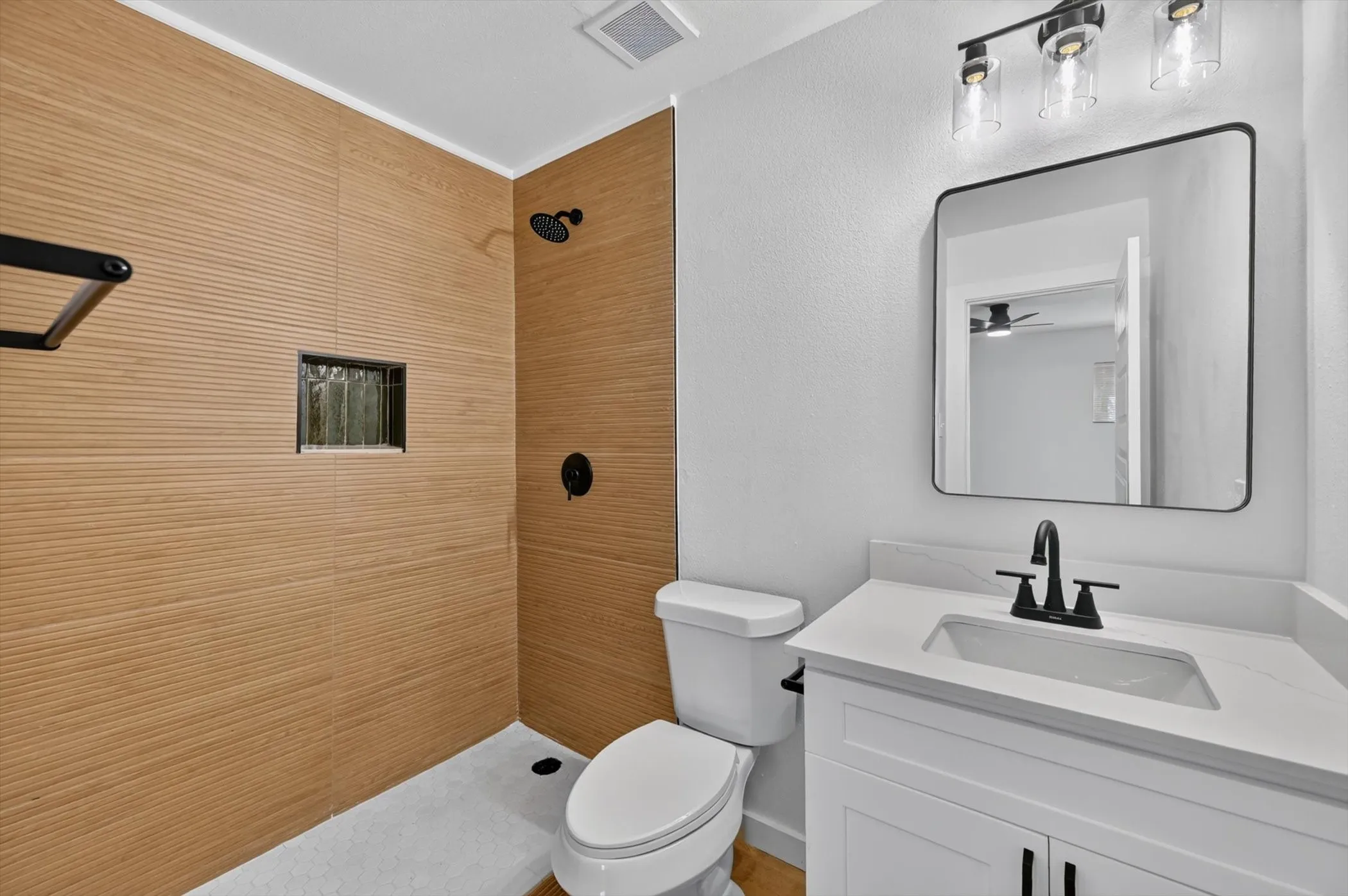 Walk-in shower with textured wall tile and a built-in niche