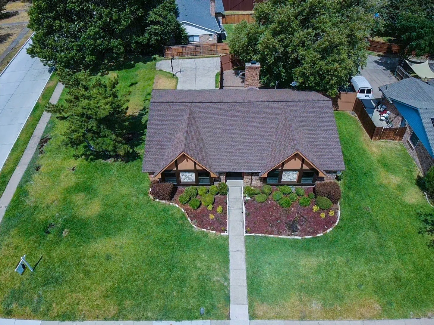 Brick exterior with a gabled roofline, front landscaping with mature plantings, and a concrete pathway leading to the entrance