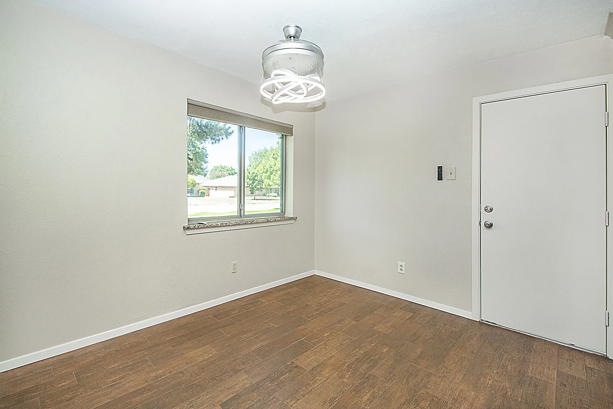 Wood-finish flooring, a contemporary ceiling light fixture, and a window with a stone sill