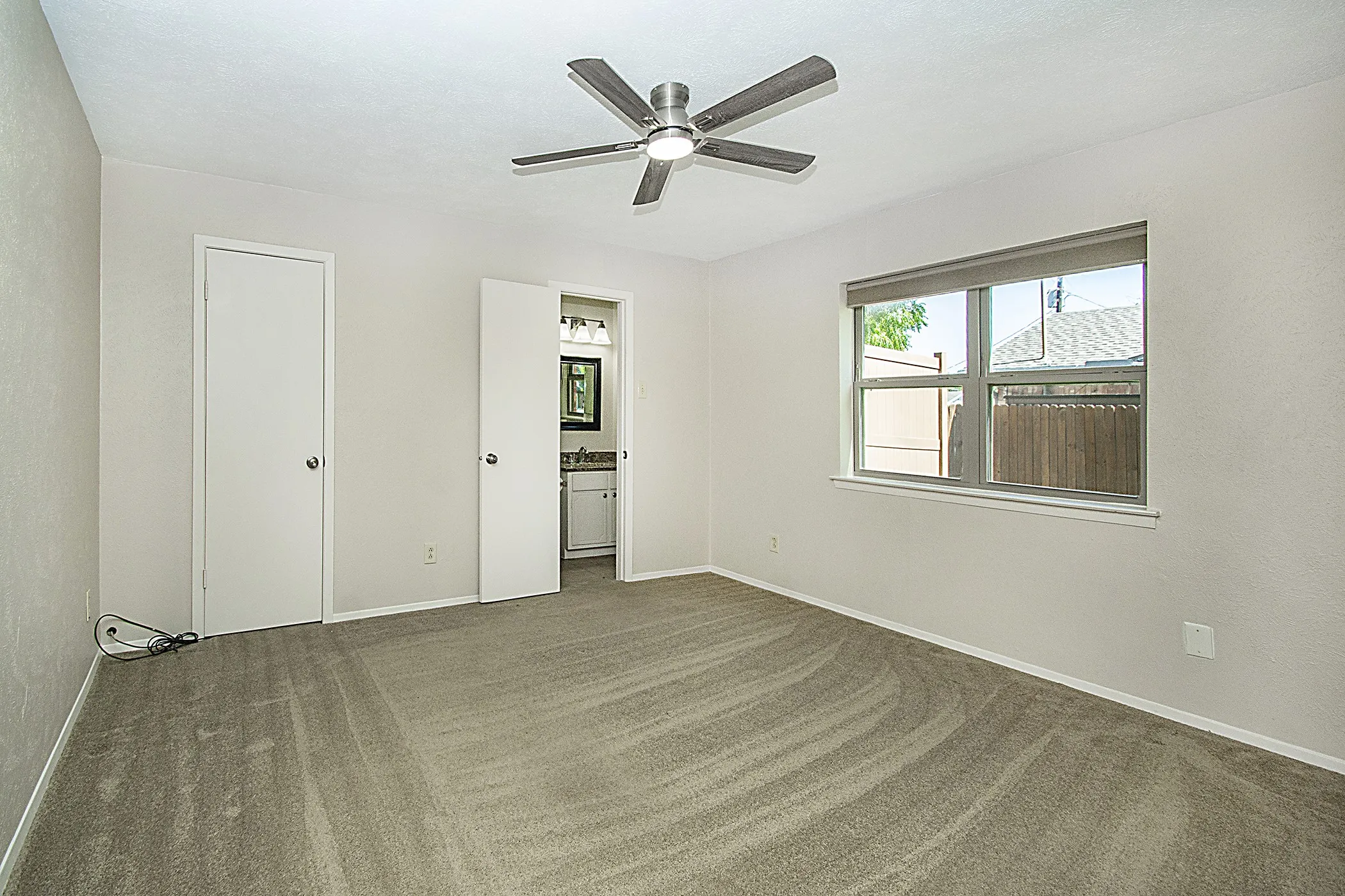 Recessed window with roller shade, ceiling fan with integrated lighting, and carpeted flooring