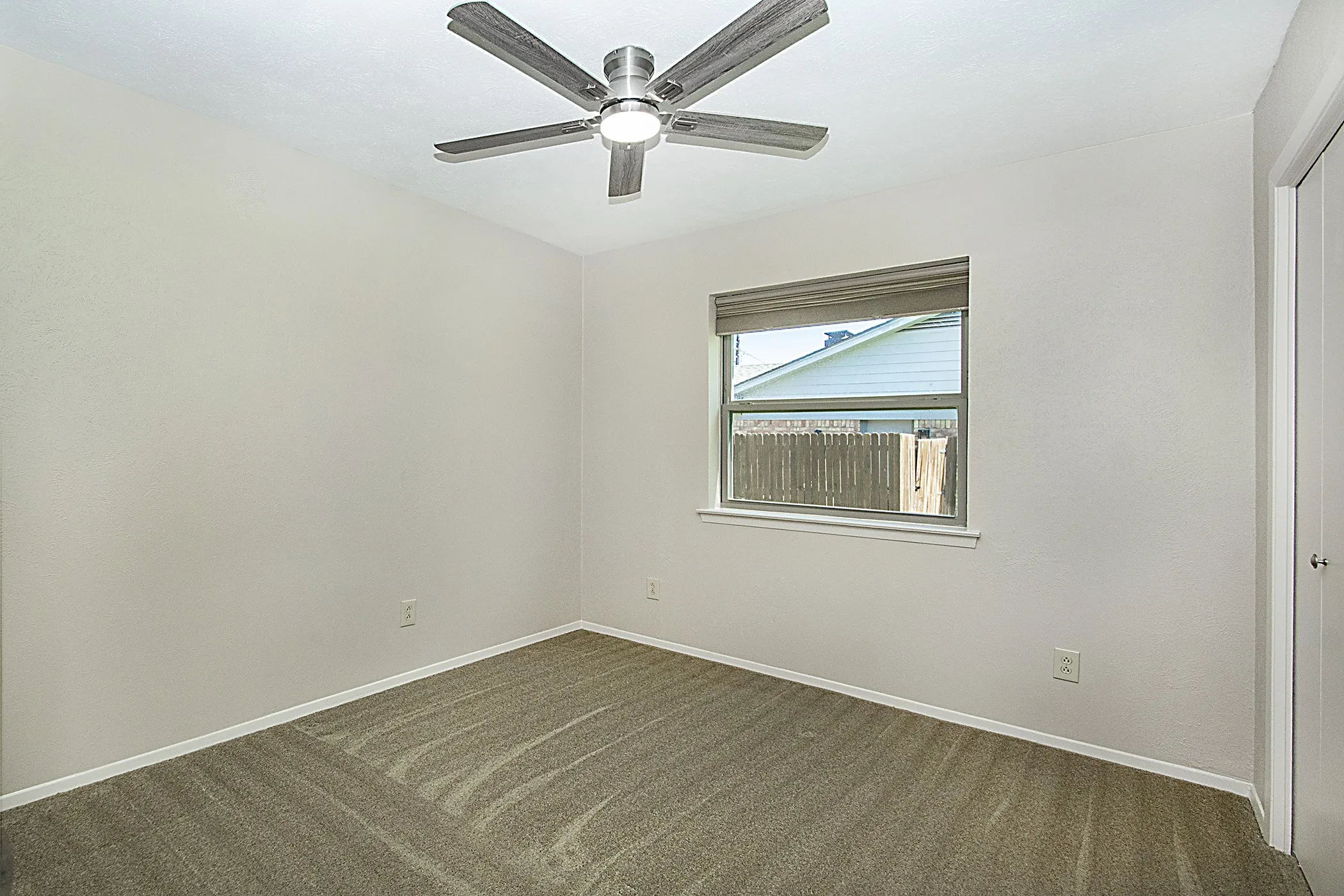 Neutral wall finishes with a ceiling fan light fixture, window with horizontal blinds, and carpeted flooring