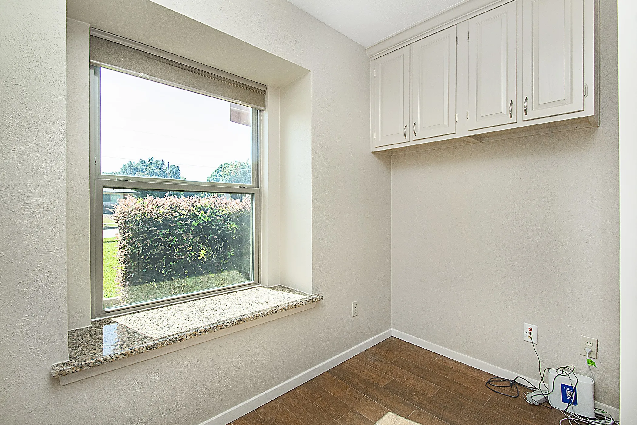Built-in upper cabinetry, granite window sill, and wood-finish flooring