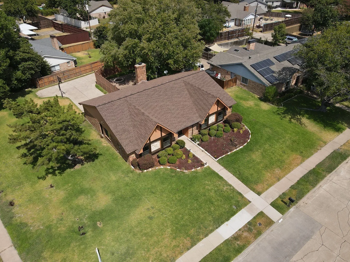 Brick exterior with a brown shingle roof and a front yard featuring a manicured planting bed