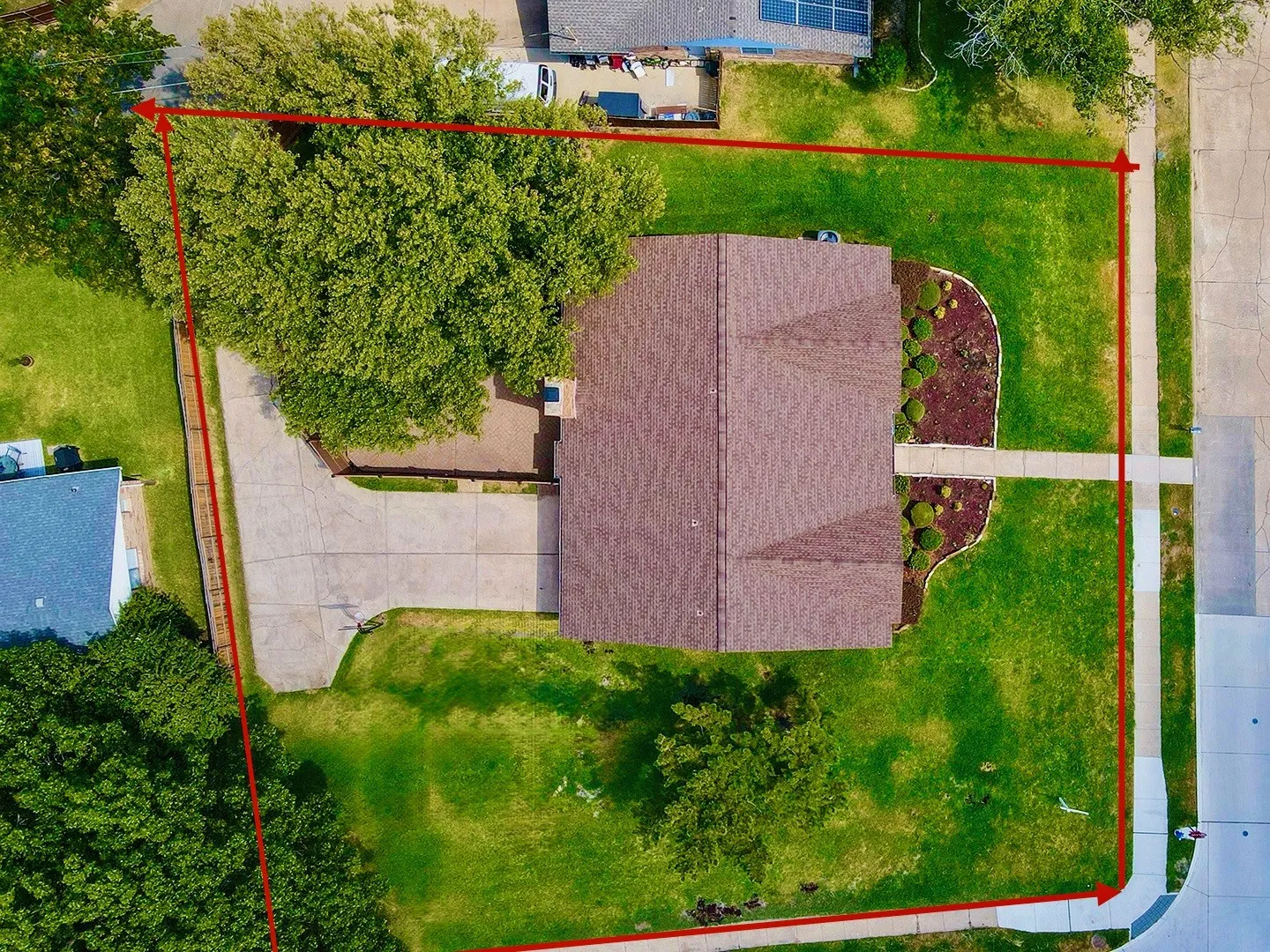 Expansive lot featuring a main residence with a gabled roof, a concrete driveway, and a front yard with manicured landscaping