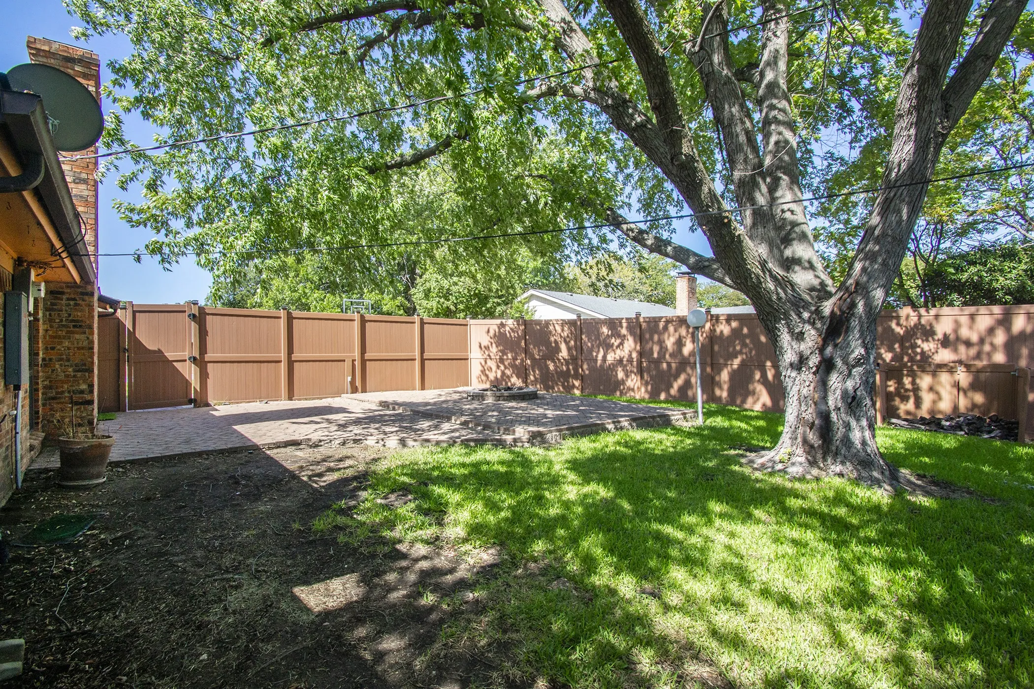 Expansive backyard featuring a mature tree, privacy fencing, a concrete patio, and a grass lawn