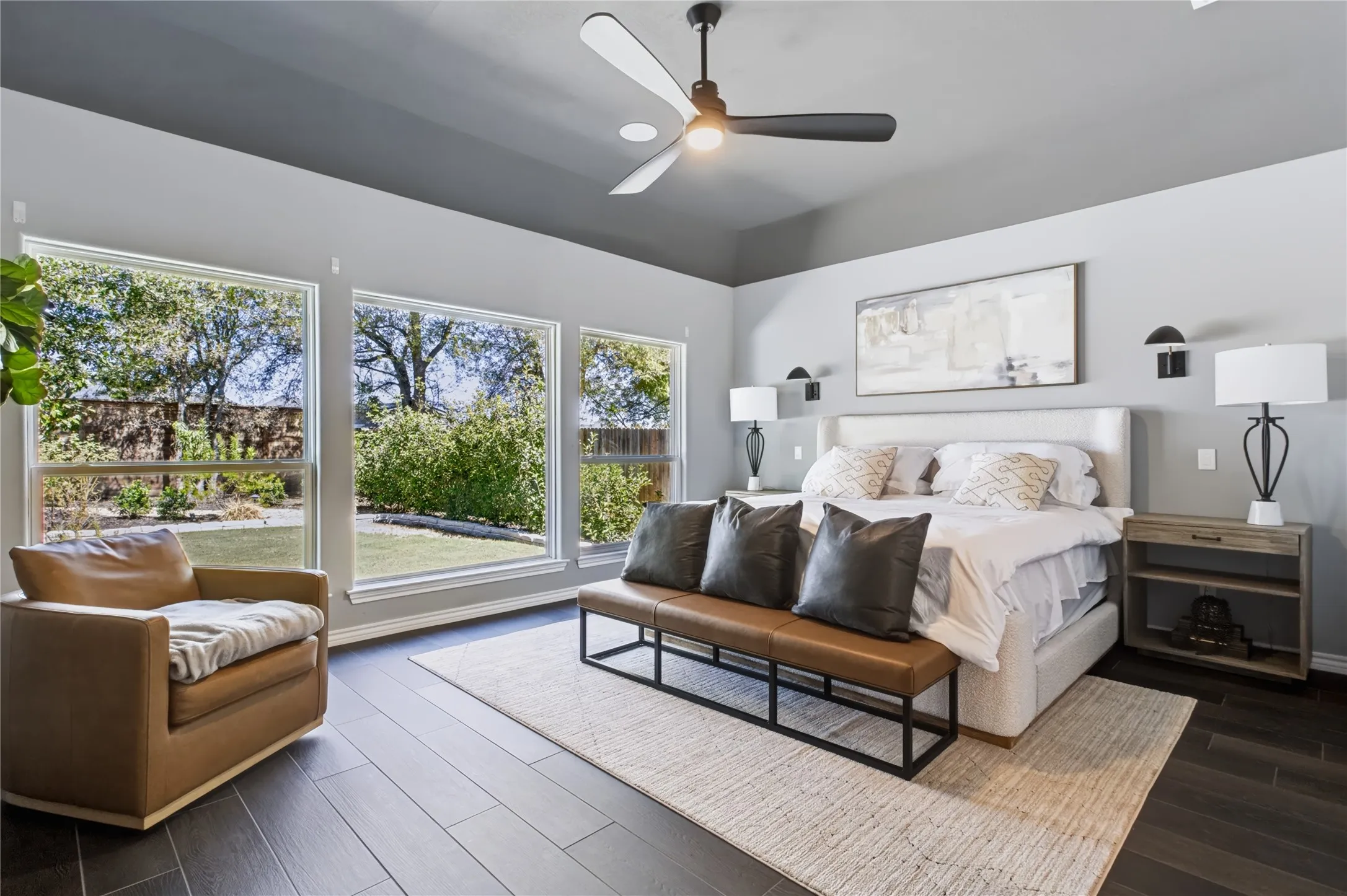 Expansive windows, wood-finish flooring, ceiling fan, recessed lighting, and wall-mounted sconces