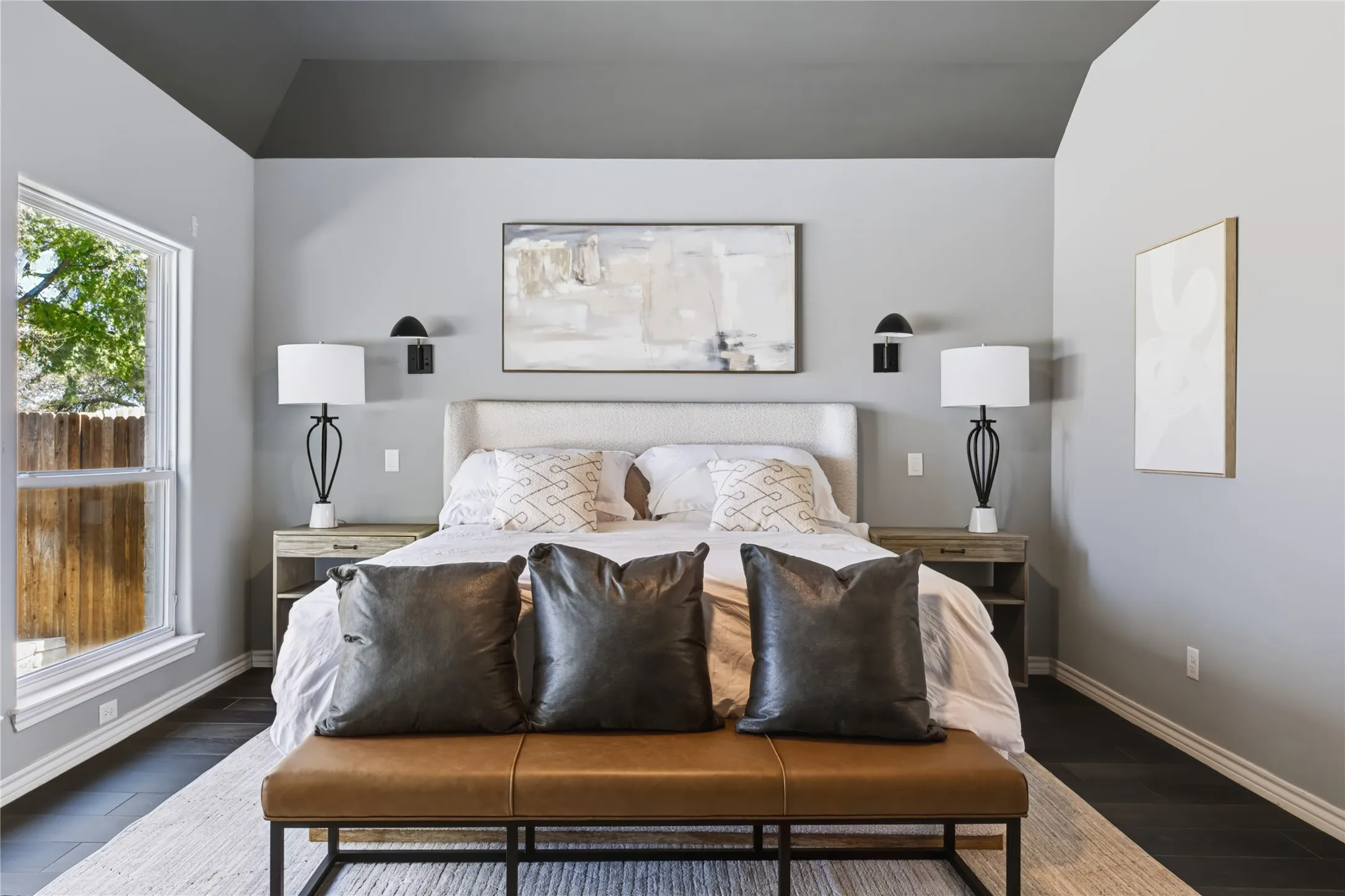 Vaulted ceiling with contrasting paint, wood-finish flooring, and a large window
