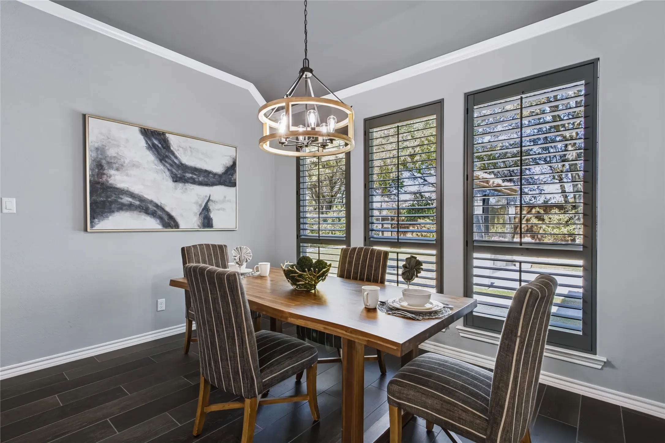 Dark wood-finish flooring, crown molding, and plantation shutters