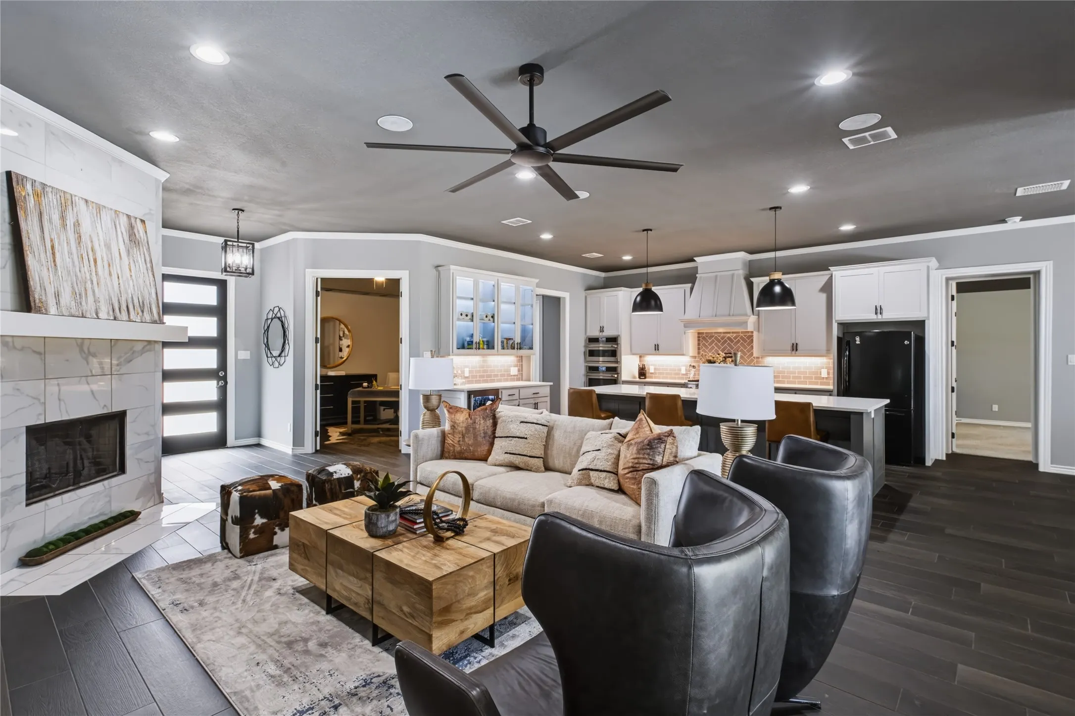 Open-concept living space featuring wood-finish flooring, a tiled fireplace, and a modern ceiling fan