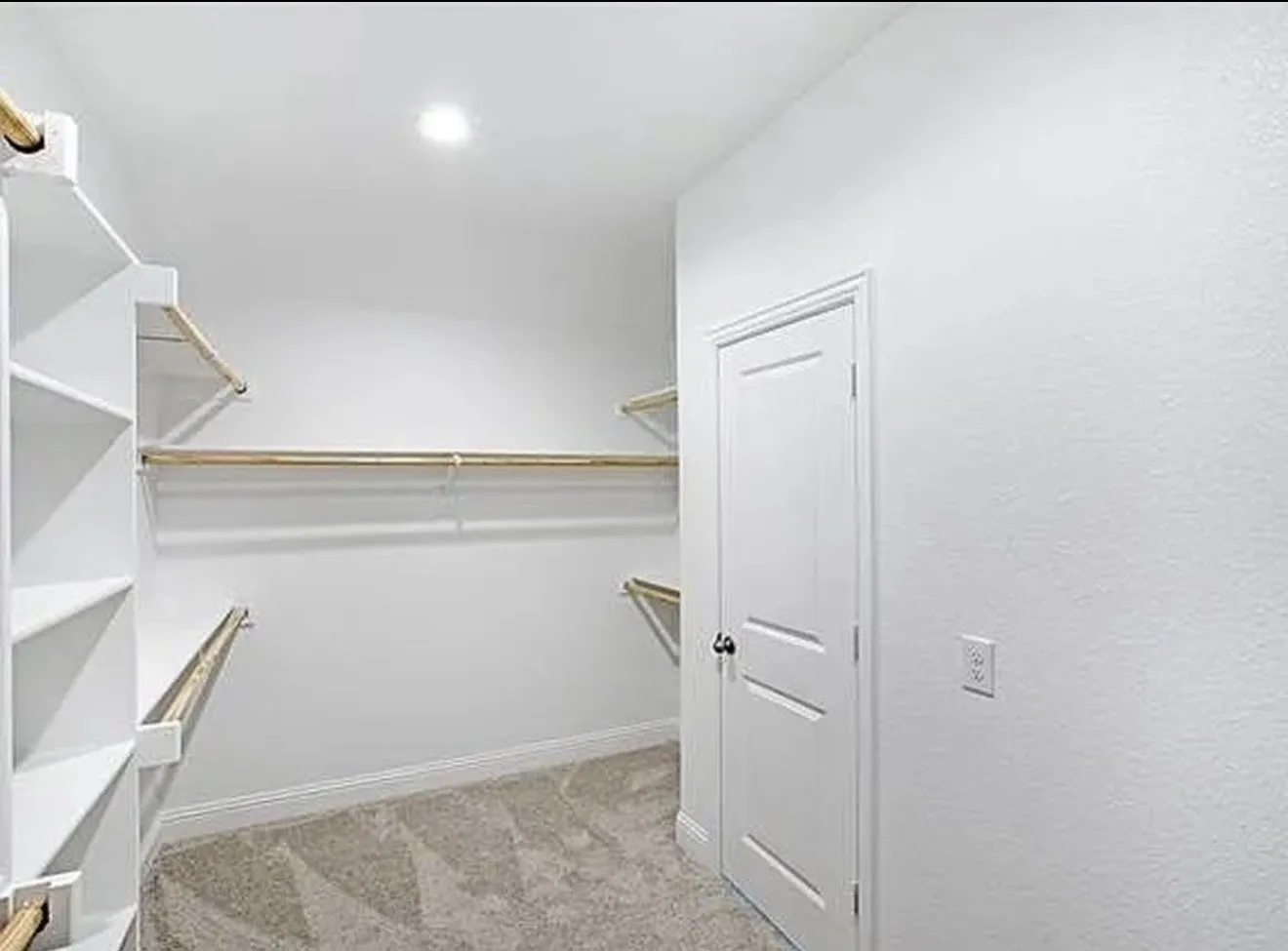 Walk-in closet featuring white built-in shelving, hanging rods, recessed lighting, and carpet flooring