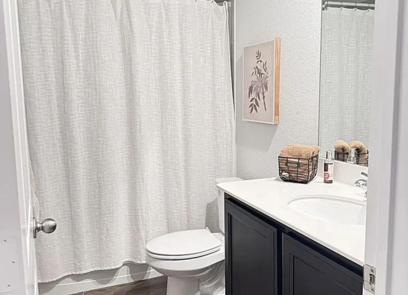 Bathroom featuring a built-in vanity with dark cabinetry, white countertop, and an integrated sink, alongside a commode and a shower area