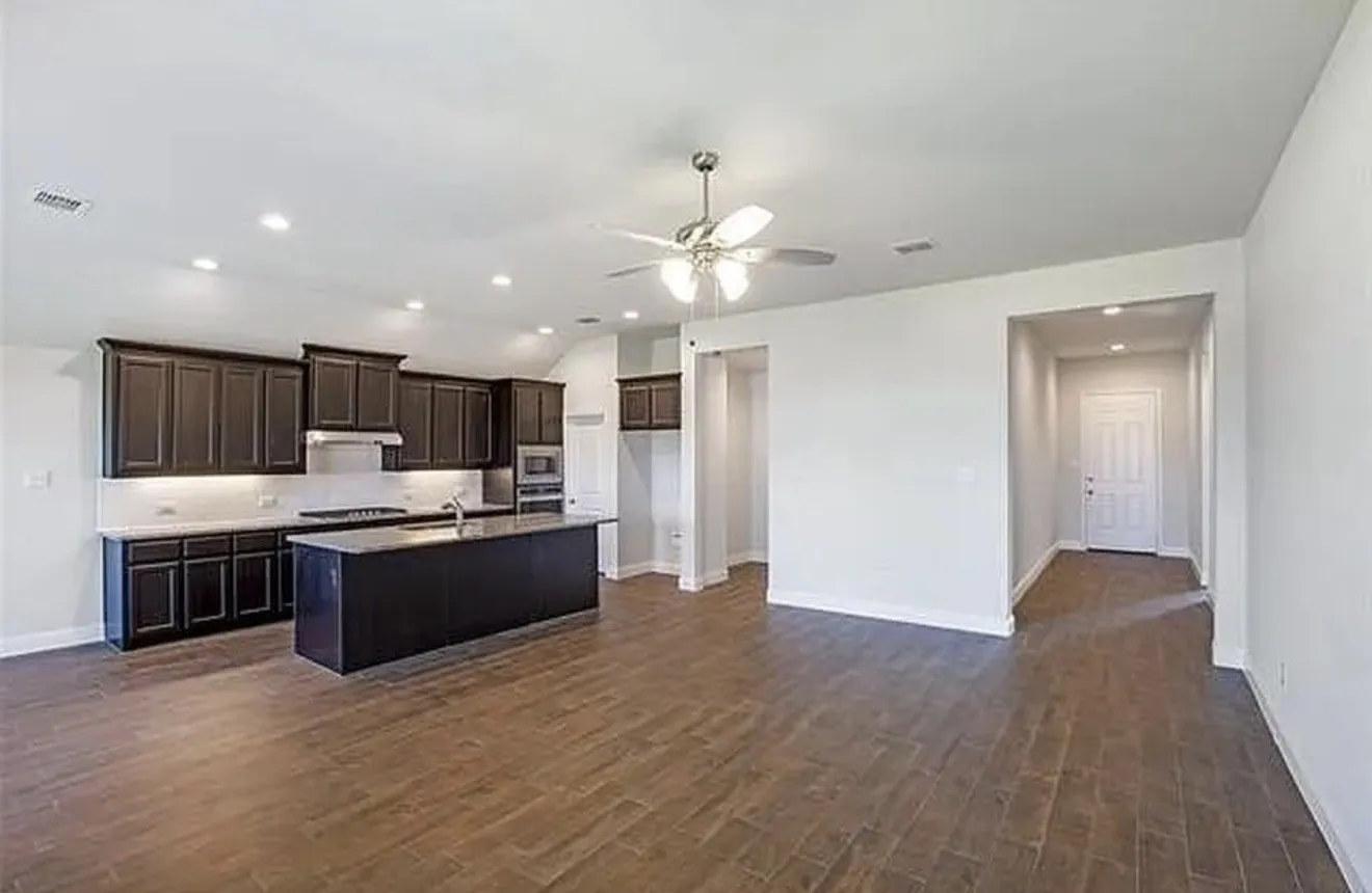 Spacious open-concept living area featuring wood-finish flooring, recessed lighting, and a ceiling fan