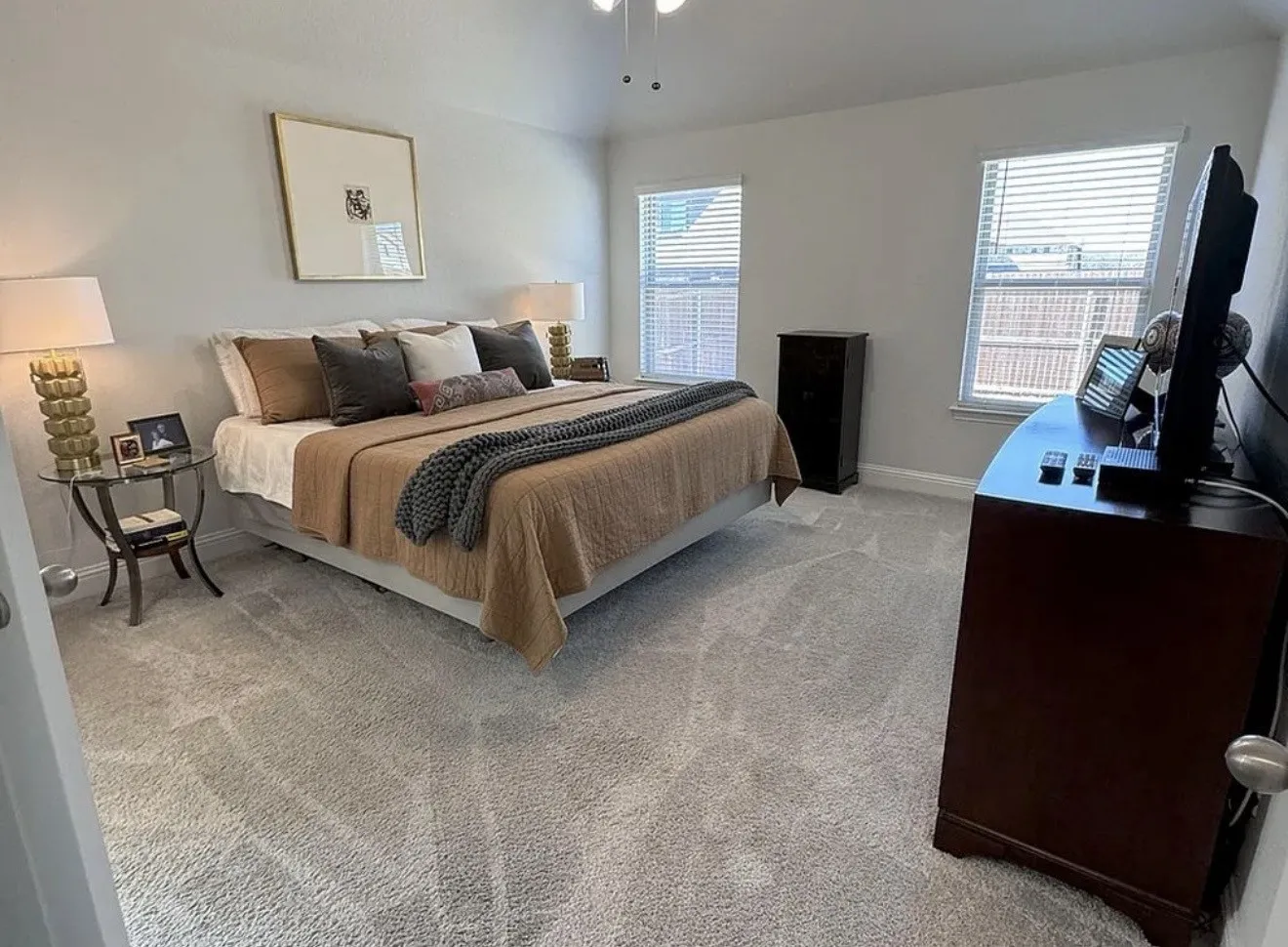 High ceilings, light gray wall paint, two windows with blinds, and light gray patterned carpeting