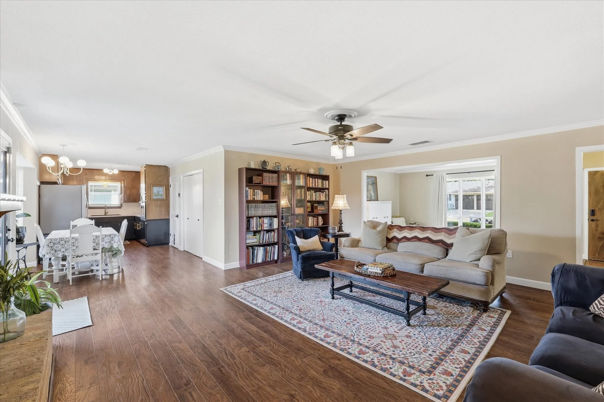 Expansive living area with wood-finish flooring, crown molding, and a ceiling fan