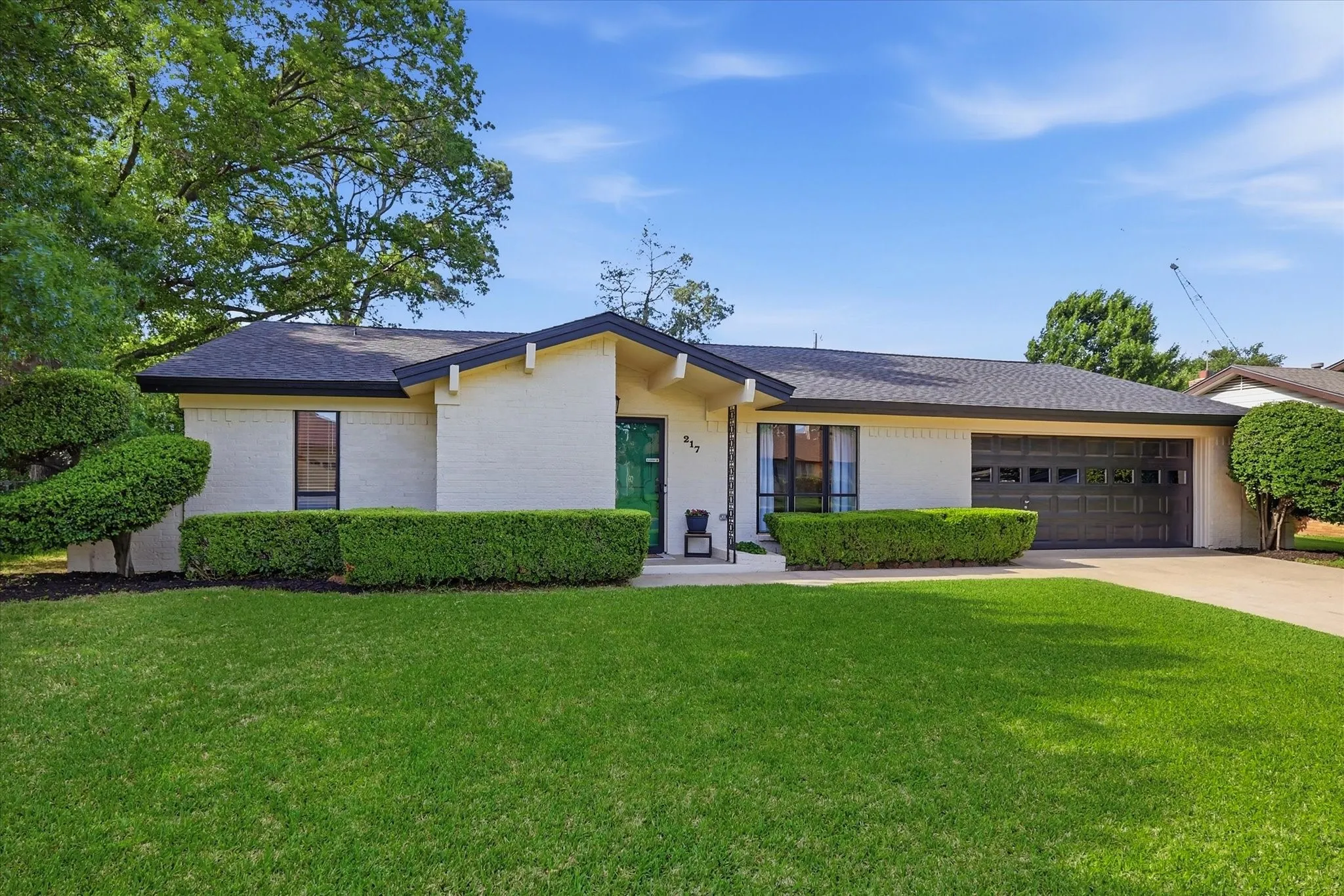 Single-story residence featuring a dark asphalt shingle roof and a two-car garage with a dark paneled door
