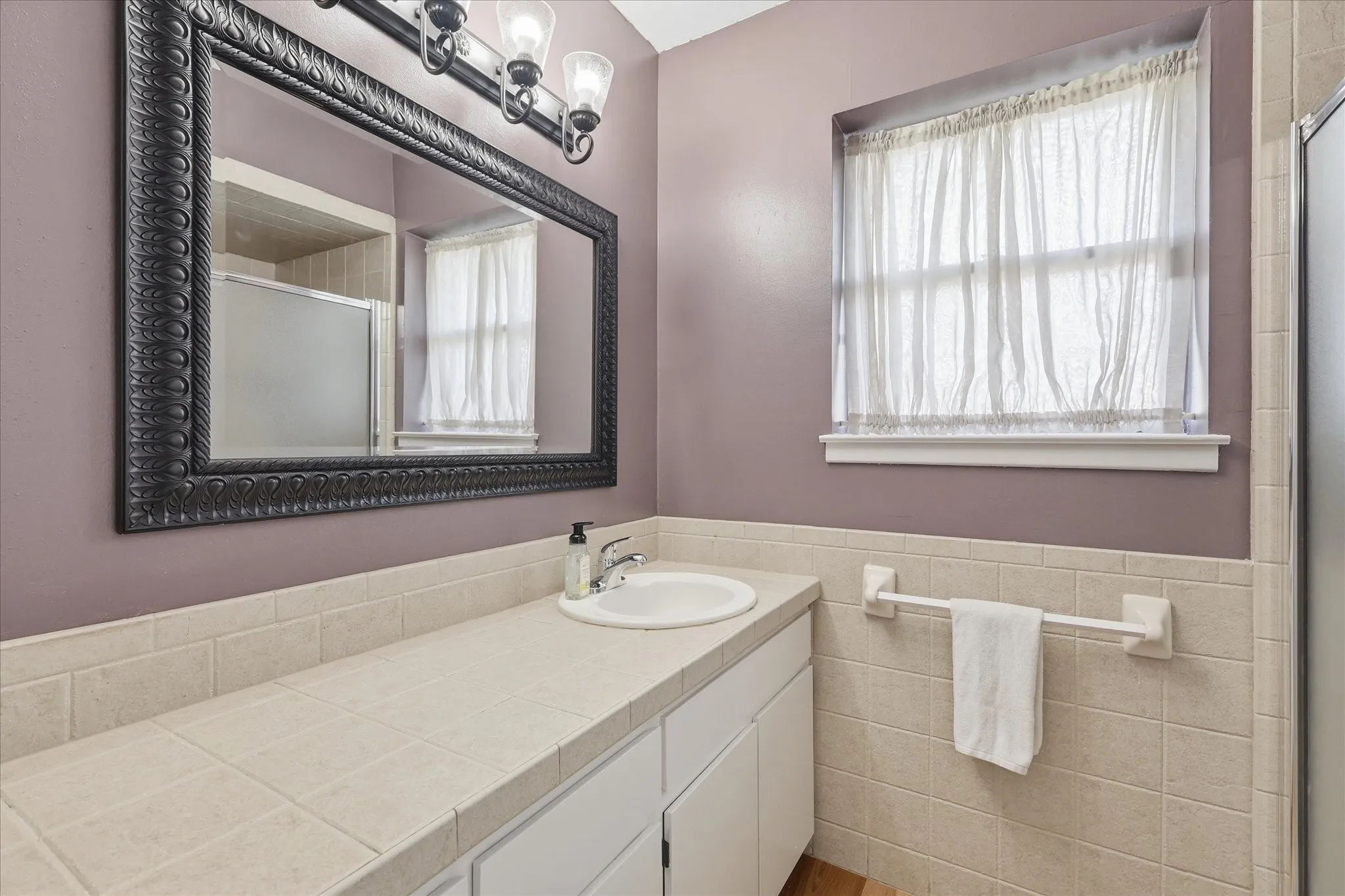Vanity with an integrated sink, a large framed mirror, and a three-light fixture
