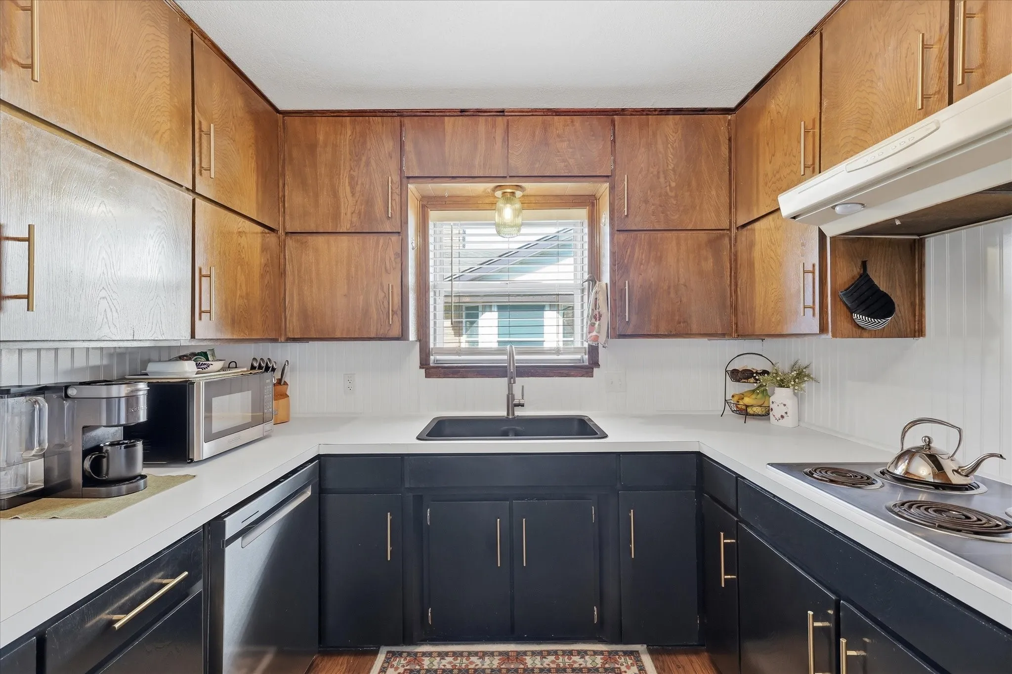 U-shaped kitchen with wood-finish upper cabinetry, dark lower cabinetry, and white countertops