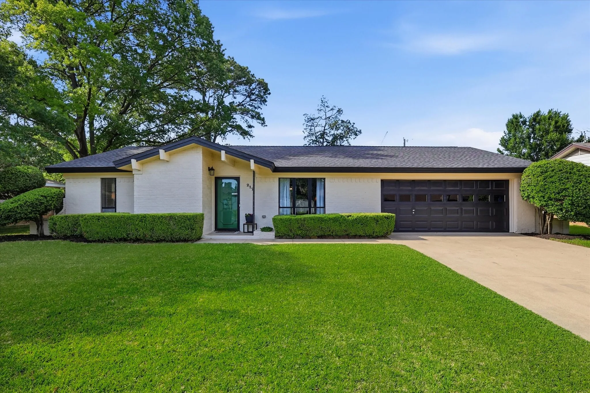 White brick exterior with a dark shingle roof