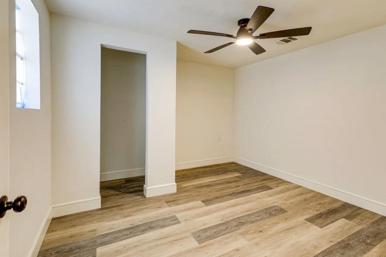 Wood-finish flooring, white walls, and a ceiling fan with integrated lighting