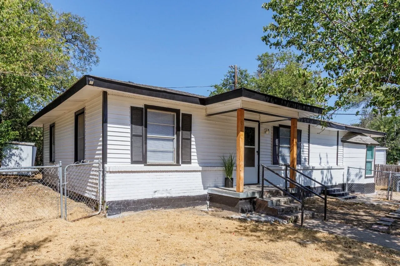 White siding exterior with a black trim roofline, accented by black shutters and a covered entry