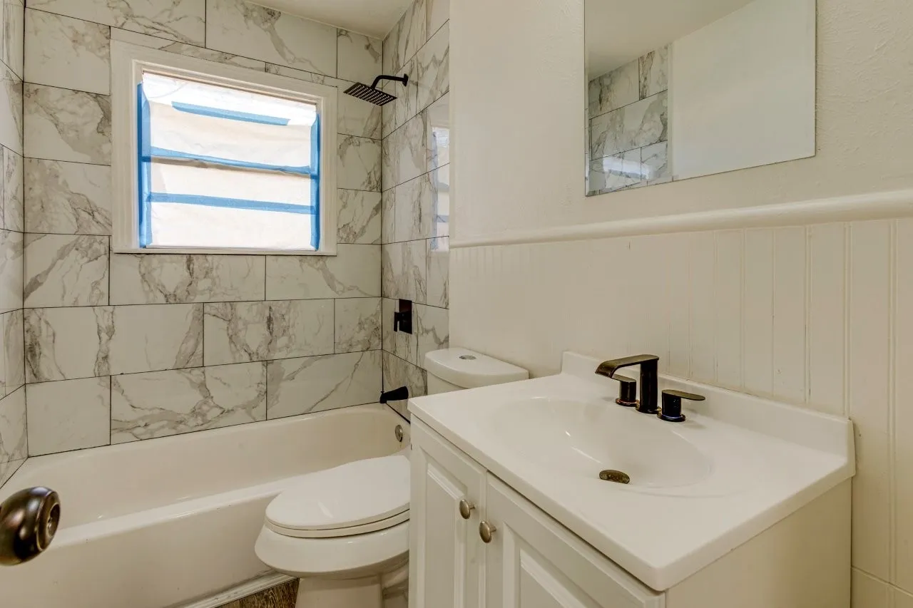 Bathroom featuring a white vanity with integrated sink, dark bronze-finish faucet, and beadboard wainscoting