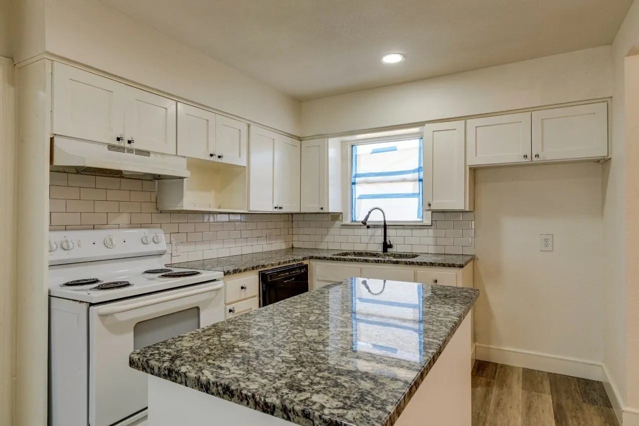 Kitchen featuring white shaker cabinetry, white subway tile backsplash, a dark stone-finish countertop, and wood-finish flooring