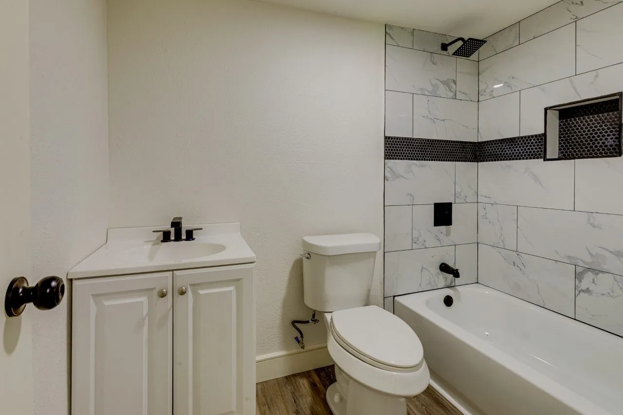 Bathroom featuring a white vanity with a single basin sink, matte black faucet, and a white toilet