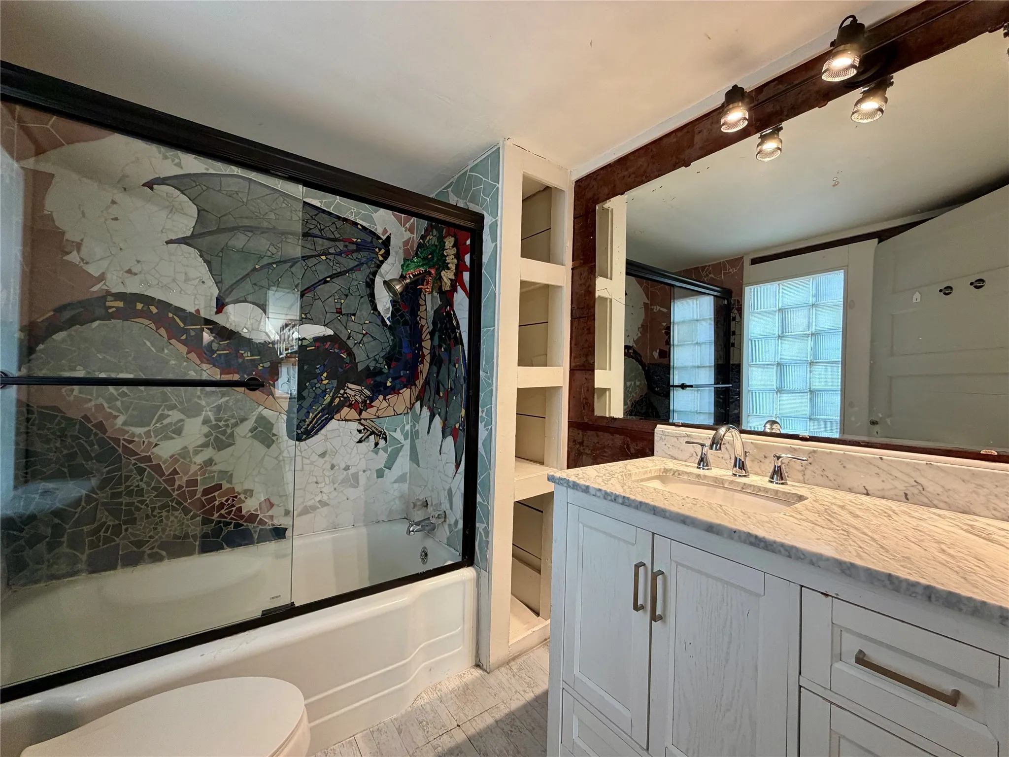 Custom mosaic shower enclosure, integrated bathtub, vanity with stone countertop, polished chrome faucet, and built-in shelving