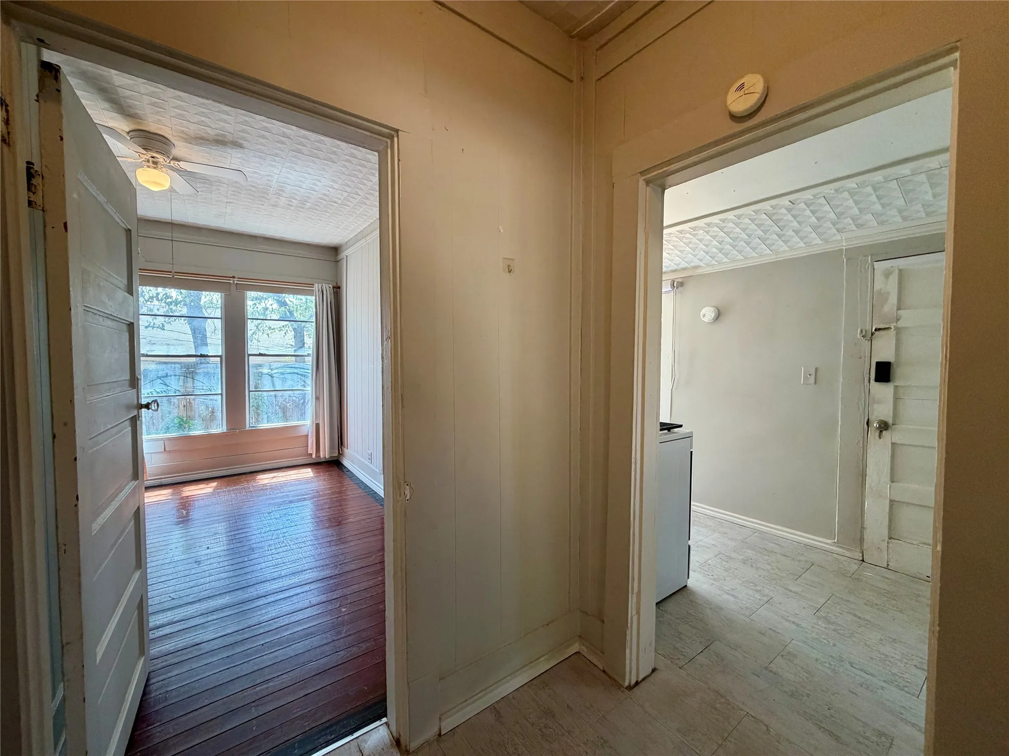 Wood-finish flooring in the foreground room, paired with multiple windows providing natural illumination