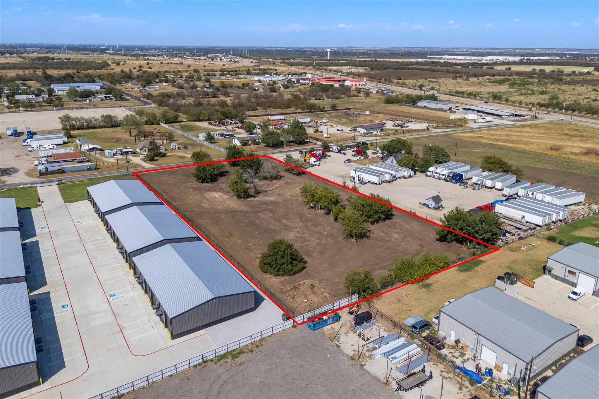 Expansive land parcel with clear boundaries, featuring scattered mature trees and open ground