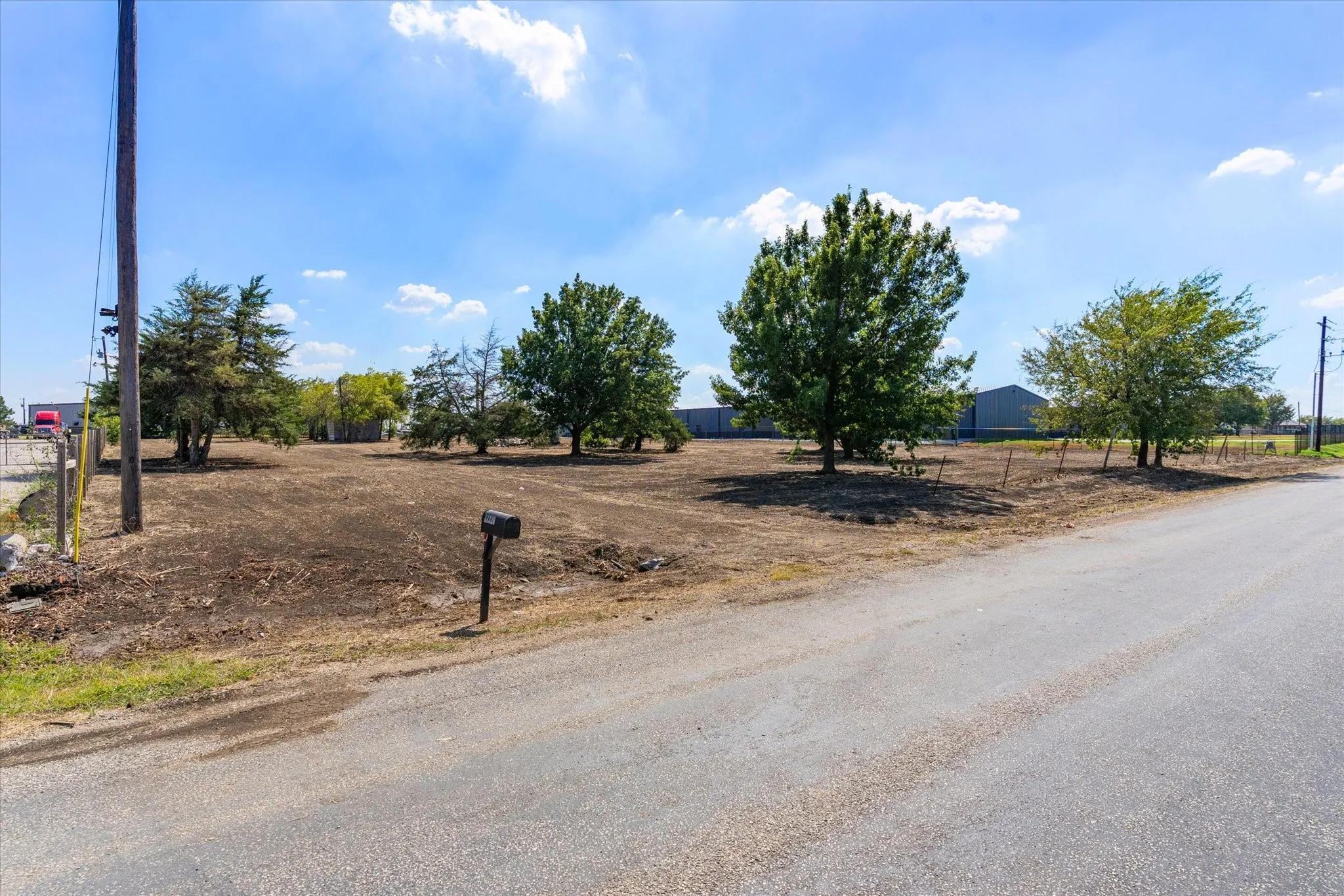 Expansive undeveloped lot featuring mature trees and a paved road