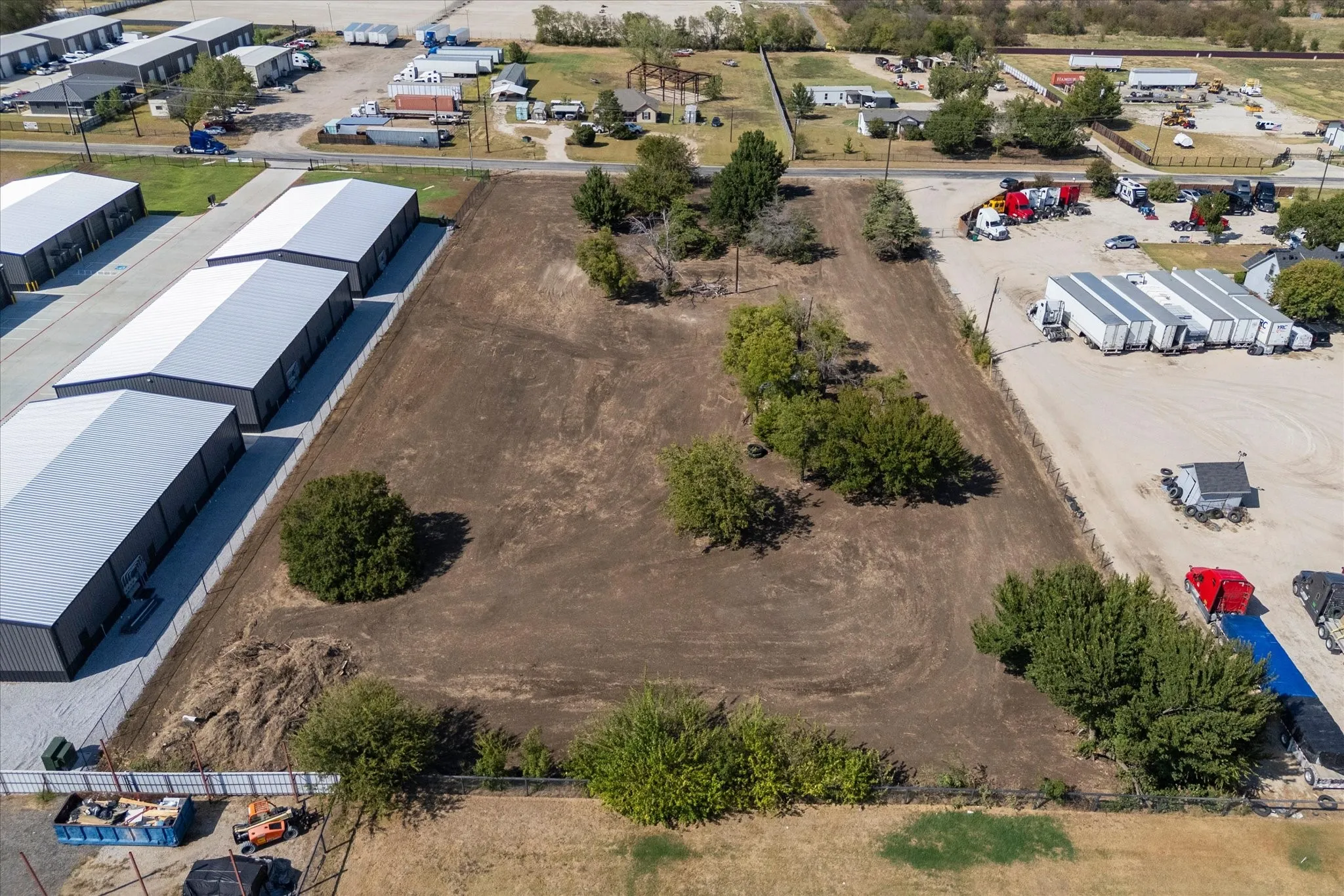 Expansive cleared lot featuring several mature trees and established perimeter fencing