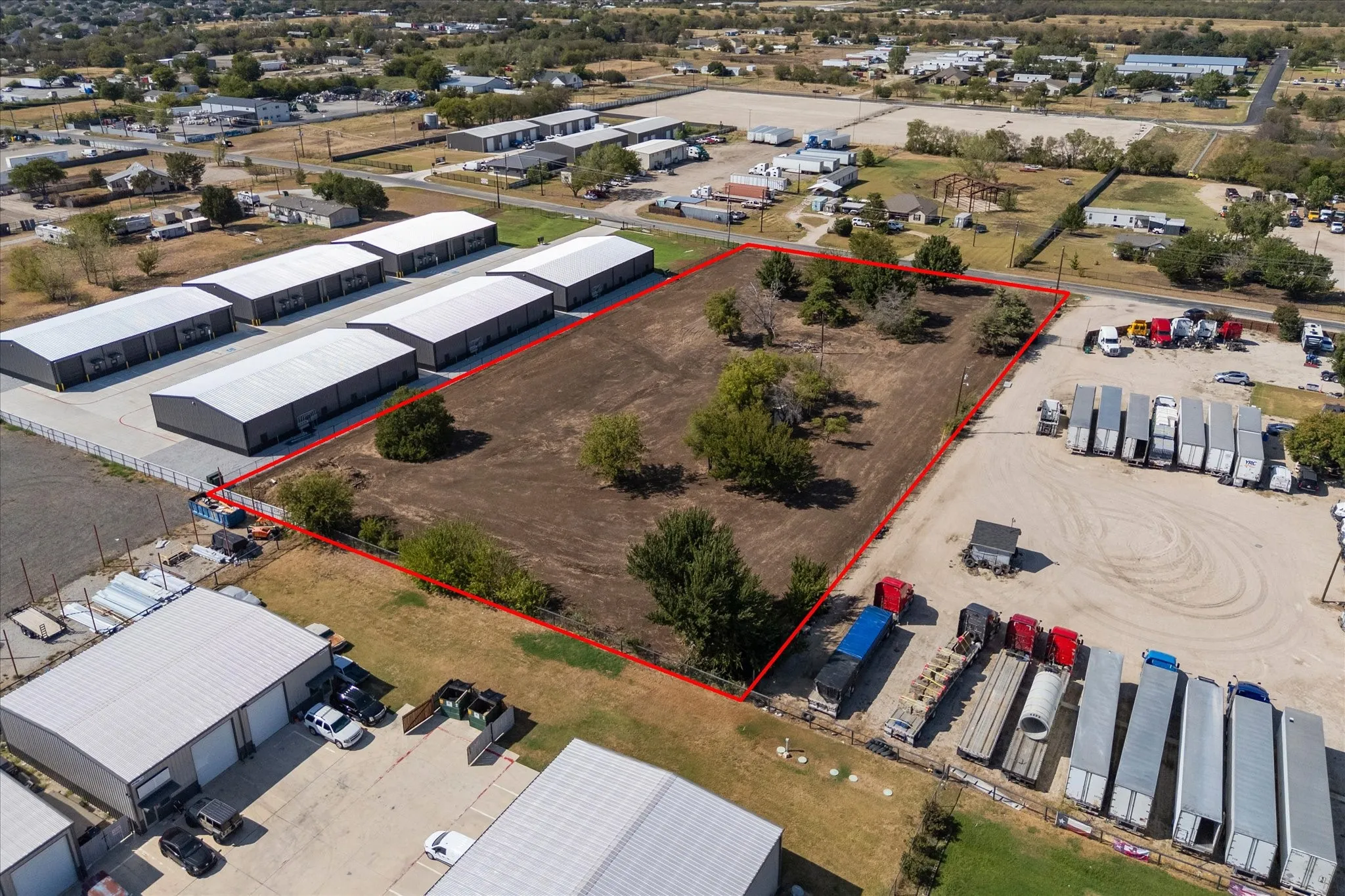 Expansive cleared parcel with mature trees and perimeter fencing