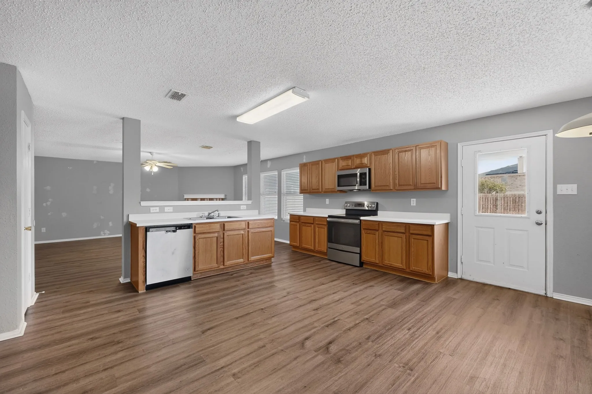 Kitchen featuring wood-finish flooring, wood cabinetry, white countertops, and stainless steel appliances