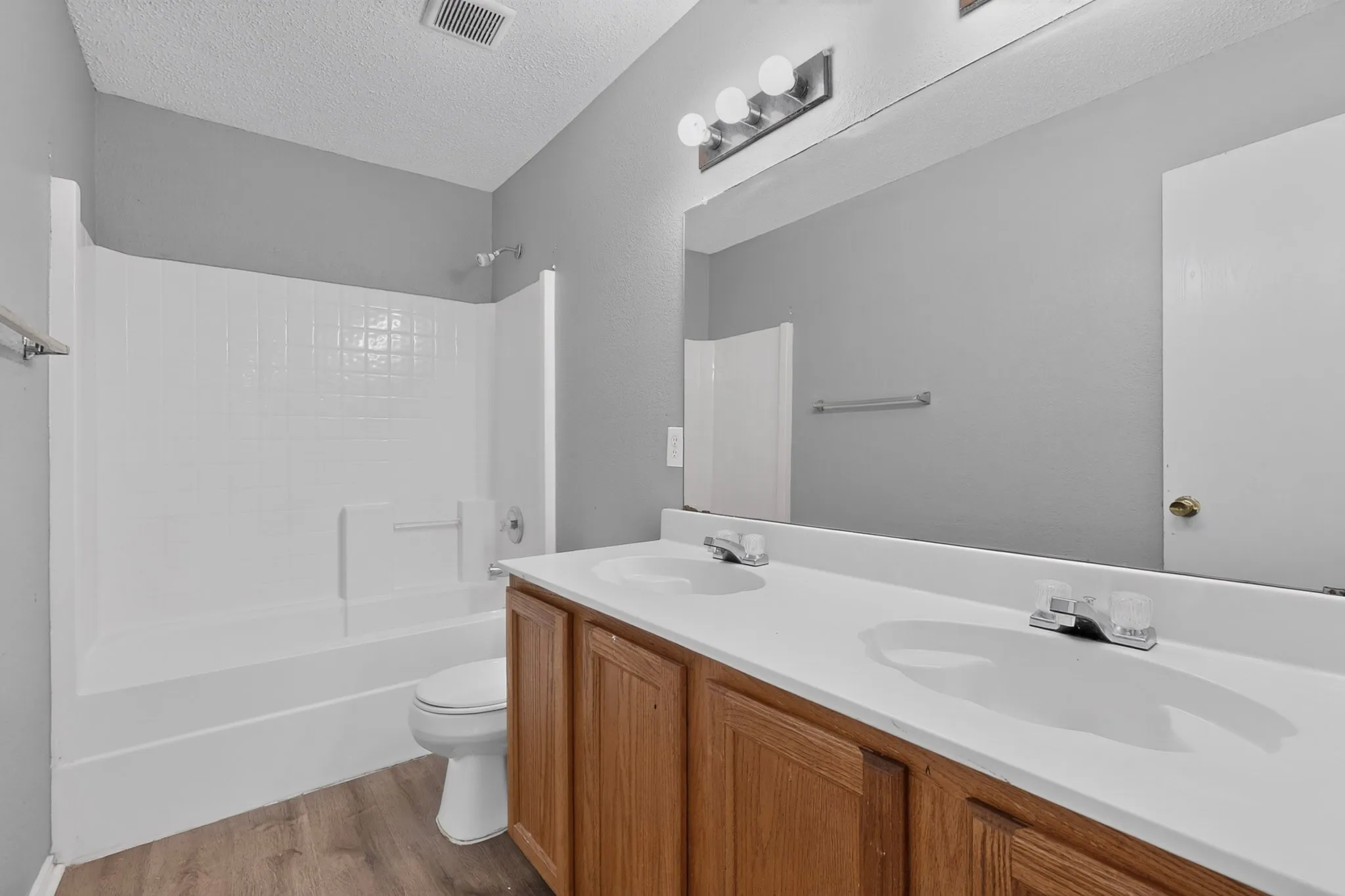 Dual vanity with white countertops, wood-finish cabinetry, and chrome fixtures