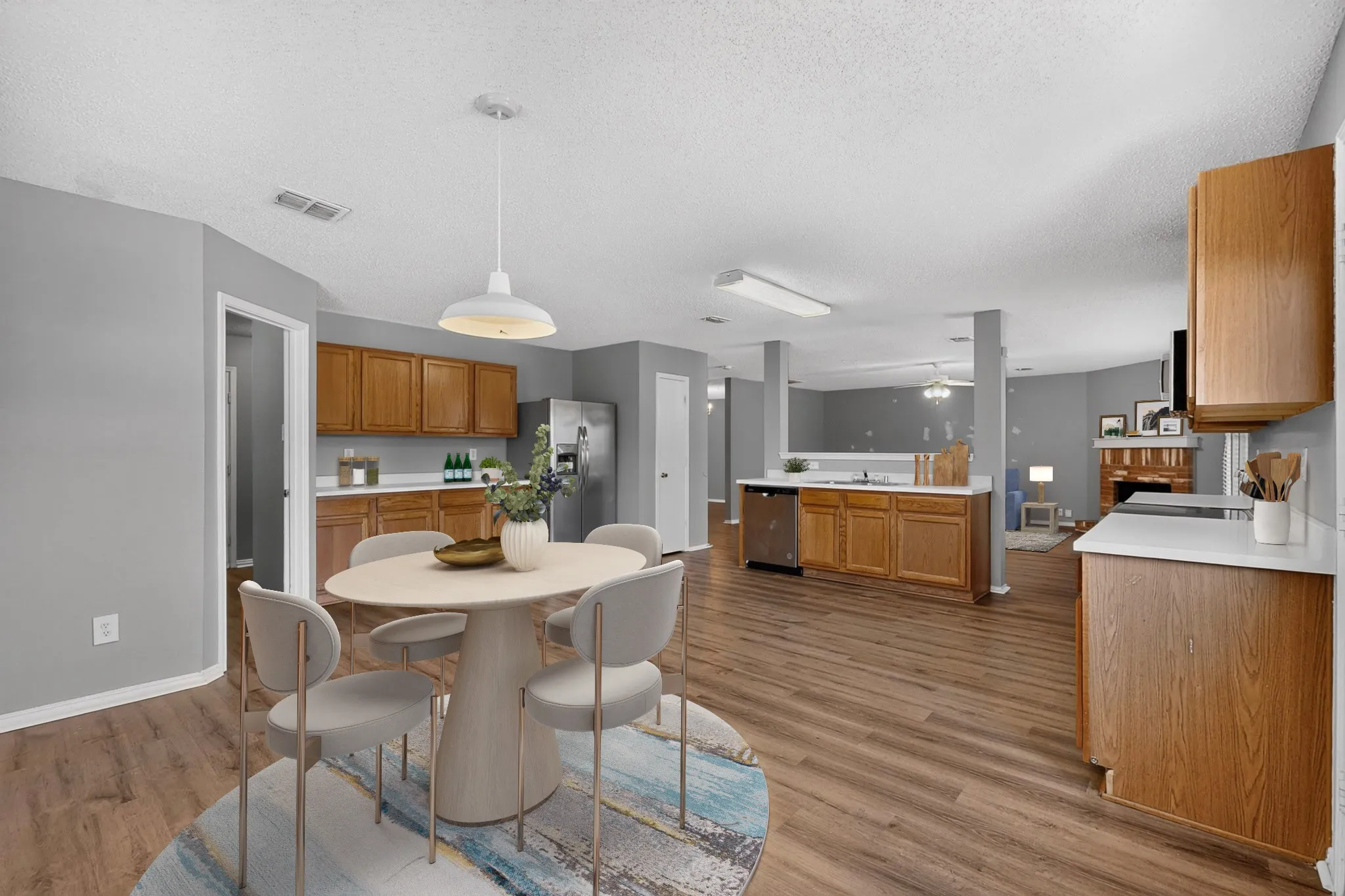 Wood-finish flooring throughout, kitchen with wood cabinetry and light countertops, stainless steel refrigerator, and recessed lighting