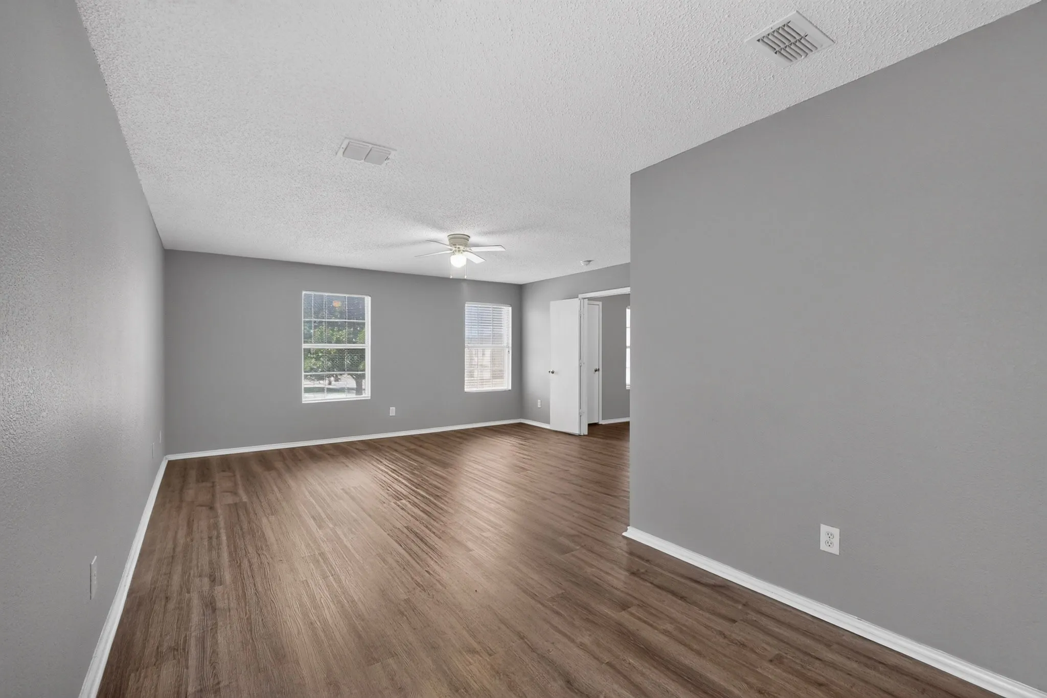 Spacious interior featuring wood-finish flooring, light gray walls, white trim, and a ceiling fan
