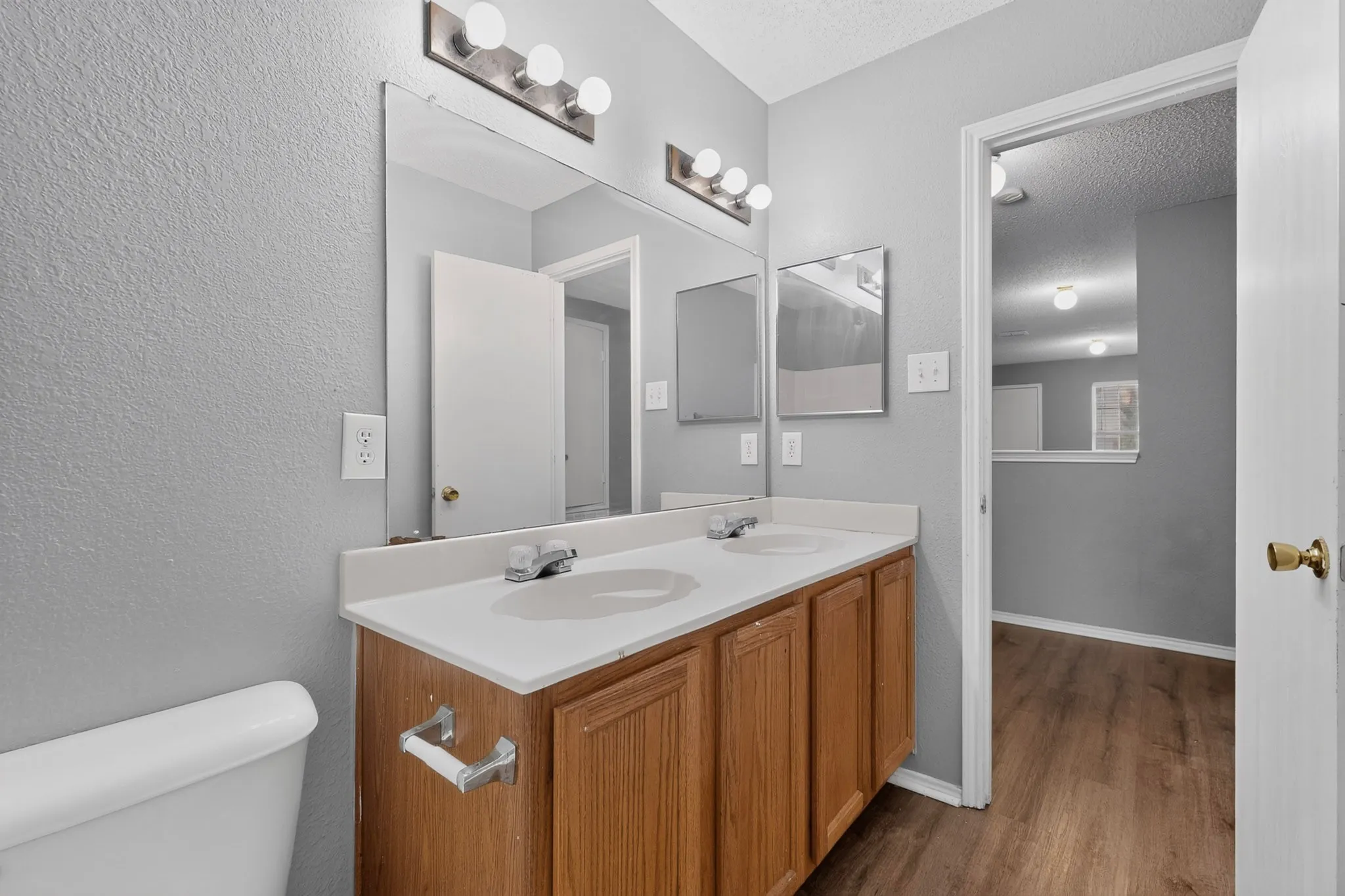 Dual basin vanity with wood-finish cabinetry and overhead vanity lighting