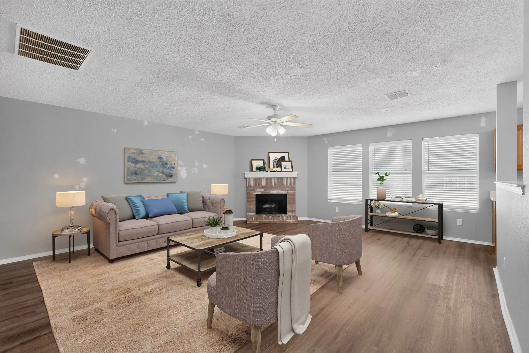 Living area featuring wood-finish flooring, a fireplace with a stone surround, multiple windows with blinds, a ceiling fan, and light gray walls