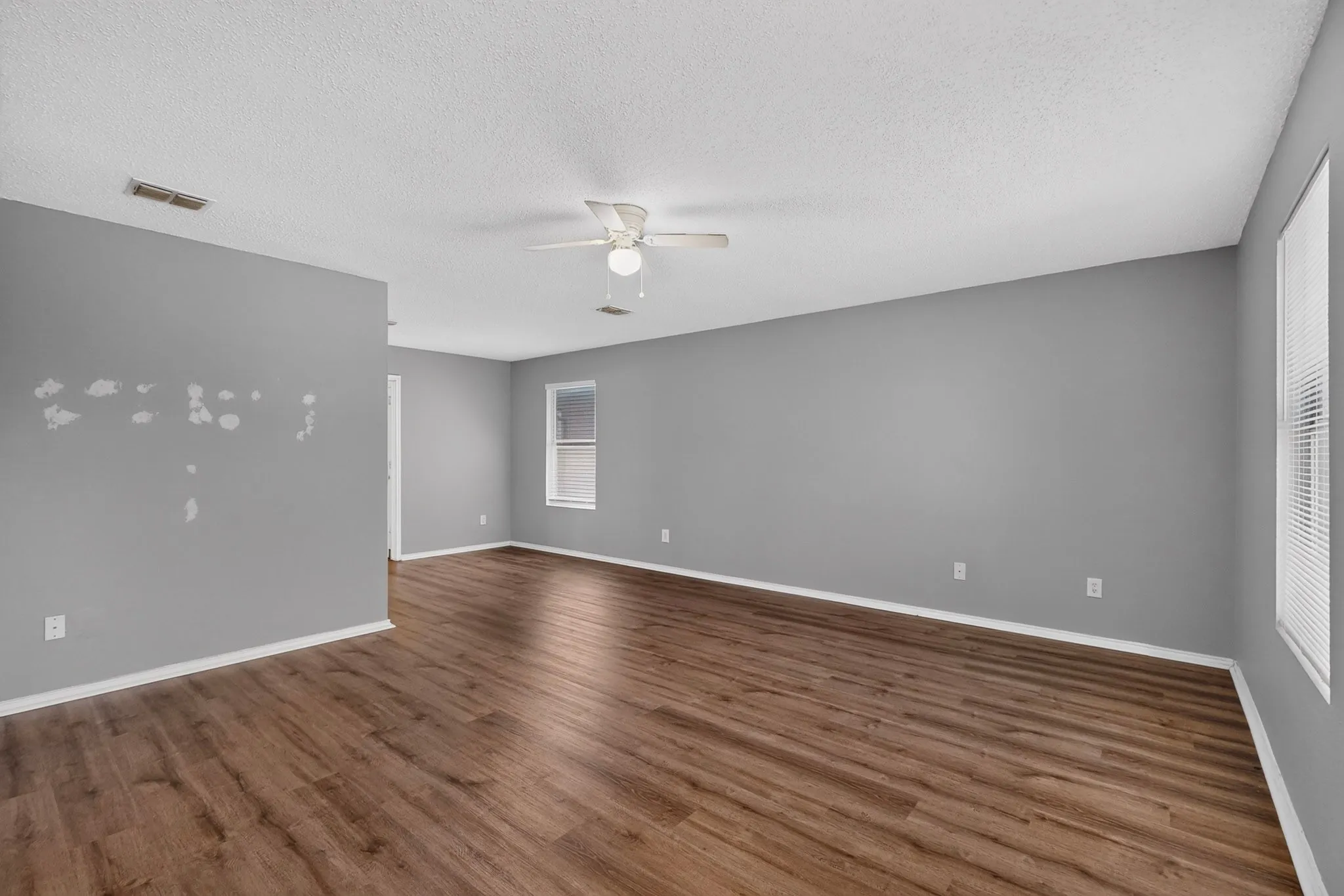 Wood-finish flooring throughout, neutral gray wall tones, and a ceiling fan with integrated lighting