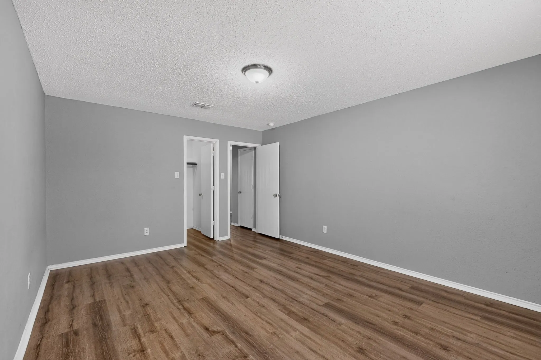Wood-finish flooring, neutral gray wall tones, and overhead lighting
