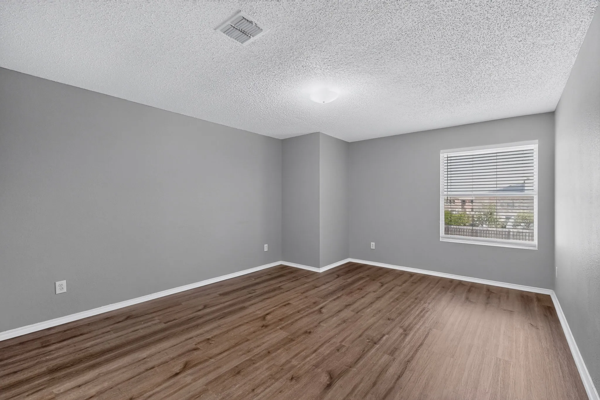 Recessed lighting, wood-finish flooring, neutral gray walls, white trim, and a window with horizontal blinds