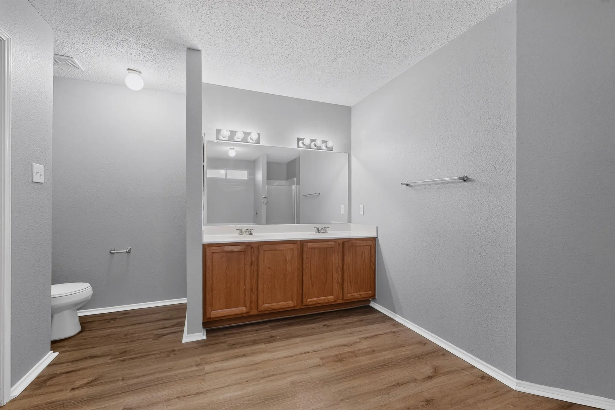 Double vanity with wood-finish cabinetry, dual sinks, and extensive mirror
