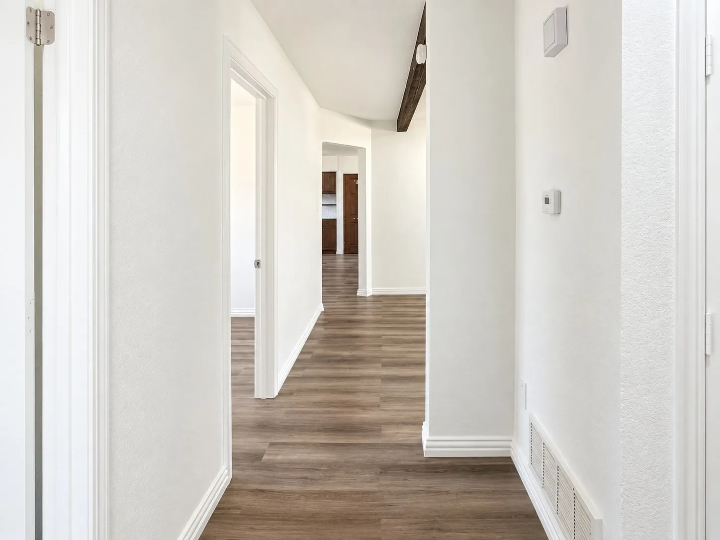 Hallway featuring wood-finish flooring, white walls, and white trim